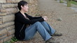 Sad woman sitting against a wall