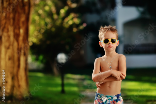 Photo: in the park outdoors only boy in shorts and sunglasses in the park outdoors only boy in shorts and sunglasses