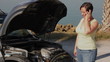 Woman with broken down car talking on her cellphone