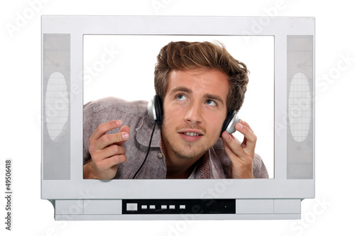 Photo: Young with headphones behind TV Young with headphones behind TV