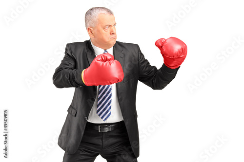 Photo: A mature businessman with red boxing gloves ready to fight A mature businessman with red boxing gloves ready to fight
