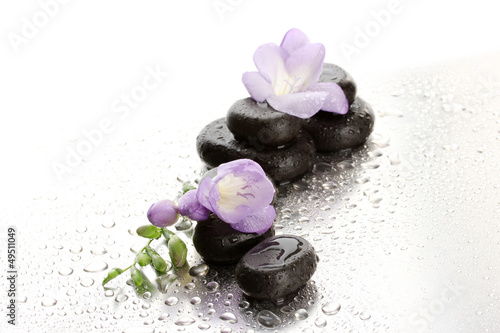 Photo: Spa stones and purple flower, on wet background Spa stones and purple flower, on wet background