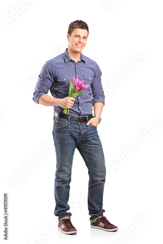 Photo: Full length portrait of a smiling guy holding flowers and lookin Full length portrait of a smiling guy holding flowers and lookin