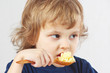 Little boy bites millet porridge from a wooden spoon