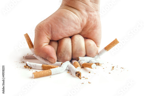 Photo: Human fist breaking cigarettes on white background Human fist breaking cigarettes on white background
