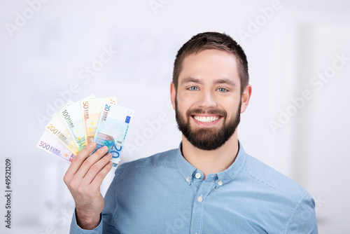 Photo: lächelnder mann hält geldscheine in der hand lächelnder mann hält geldscheine in der hand