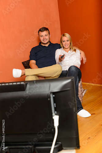 Photo: Smiling couple changing channels watching television evening Smiling couple changing channels watching television evening
