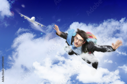 Photo: Young businessman flying with parachute on back Young businessman flying with parachute on back