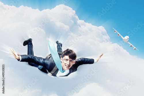 Photo: Young businessman flying with parachute on back Young businessman flying with parachute on back