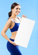 Woman in fitnesswear showing signboard, over blue