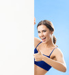 Woman in fitnesswear showing signboard, over blue