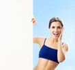 Woman in fitnesswear showing signboard, over blue