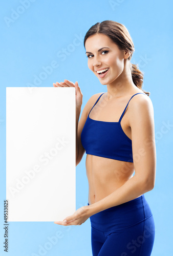 Photo: Woman in fitnesswear showing signboard, over blue Woman in fitnesswear showing signboard, over blue