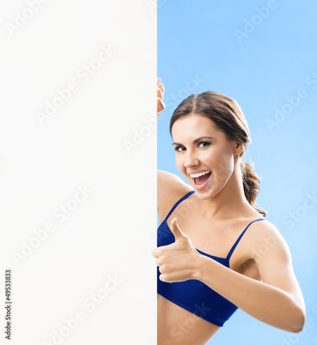 Photo: Woman in fitnesswear showing signboard, over blue Woman in fitnesswear showing signboard, over blue