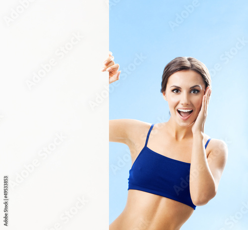 Photo: Woman in fitnesswear showing signboard, over blue Woman in fitnesswear showing signboard, over blue