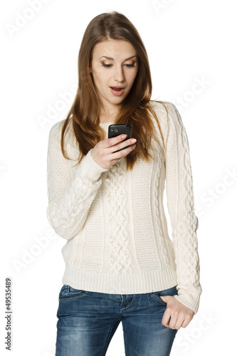 Photo: Surprised youn woman reading a sms on cell phone Surprised youn woman reading a sms on cell phone