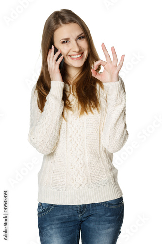 Photo: Happy woman talking on cell phone and showing OK sign Happy woman talking on cell phone and showing OK sign
