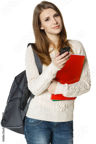Photo: Woman student with backpack and books dialing cell phone Woman student with backpack and books dialing cell phone