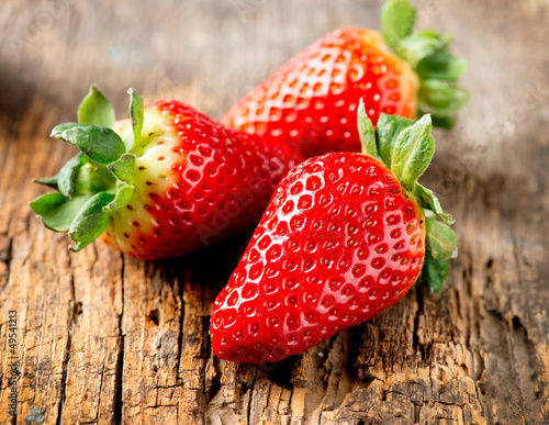 Photo: Strawberry over Wooden Background. Strawberries close-up Strawberry over Wooden Background. Strawberries close-up