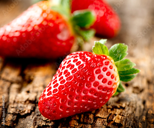 Photo: Strawberry over Wooden Background. Strawberries close-up Strawberry over Wooden Background. Strawberries close-up