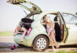 Foto: Two beautiful girls sitting in broken car and waiting for help Two beautiful girls sitting in broken car and waiting for help