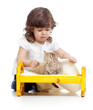 curly child girl playing with kitten as mother with baby