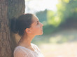 Photo: Thoughtful girl leaning on tree and looking on copy space Thoughtful girl leaning on tree and looking on copy space