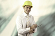 Photo: Young architect wearing a protective helmet standing on the buil Young architect wearing a protective helmet standing on the buil