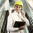 Photo: Young architect wearing a protective helmet standing on the buil Young architect wearing a protective helmet standing on the buil