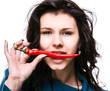 woman holding red hot chili pepper in mouth