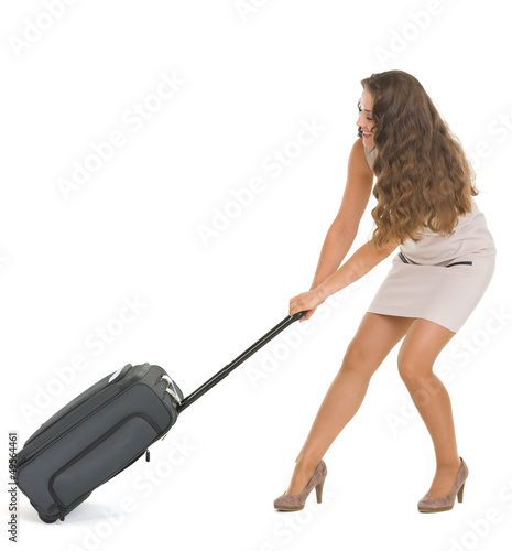 Photo: Young traveling woman pulling heavy suitcase on wheels Young traveling woman pulling heavy suitcase on wheels