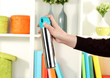 Sprayed air freshener in hand on white shelves background