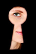 Photo: Woman eye looking through hole in keyhole, on black background Woman eye looking through hole in keyhole, on black background