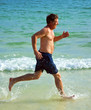 man is running along the beautiful beach, enjoying the water