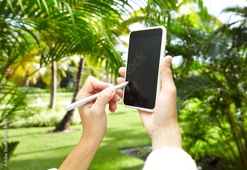 Photo: Woman with a smartphone in tropical garden. Woman with a smartphone in tropical garden.