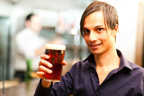 Photo: Young man having a drink in a bar Young man having a drink in a bar