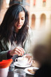Young woman drinking coffee in a cafe outdoors. 