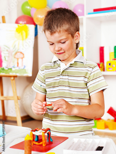 Photo: Child painting at easel. Child painting at easel.