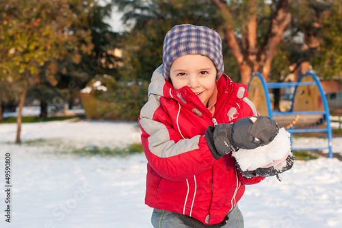 Photo: Young kid having fun in the snow with snowball. Young kid having fun in the snow with snowball.