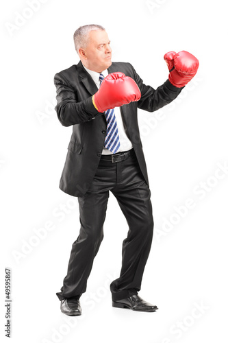 Photo: Mature businessman with red boxing gloves ready to fight Mature businessman with red boxing gloves ready to fight