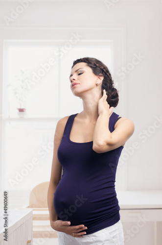 Photo: Pregnant woman standing with a pain in the neck Pregnant woman standing with a pain in the neck