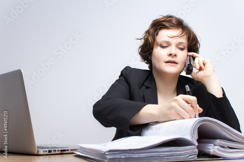 Photo: Junge Geschäftsfrau telefoniert am Arbeitsplatz Junge Geschäftsfrau telefoniert am Arbeitsplatz