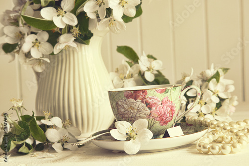Photo: Tea cup with apple blossoms on table Tea cup with apple blossoms on table