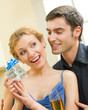 Cheerful amorous couple with gifts, indoors