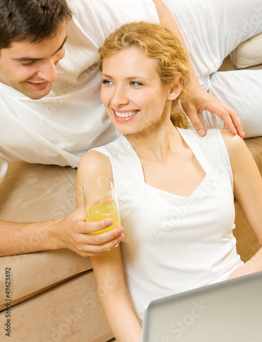 Photo: Cheerful couple with laptop, at home Cheerful couple with laptop, at home