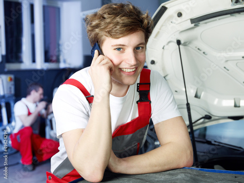 Photo: Master mechanic in a garage calls a customer Master mechanic in a garage calls a customer