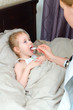 Pediatrician visiting sick child at home and giving medicine