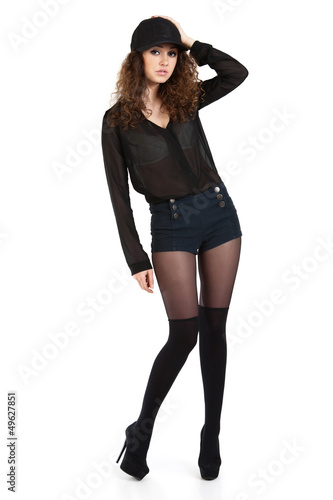 Photo: Attractive curly girl in black shorts and a baseball cap posing. Attractive curly girl in black shorts and a baseball cap posing.