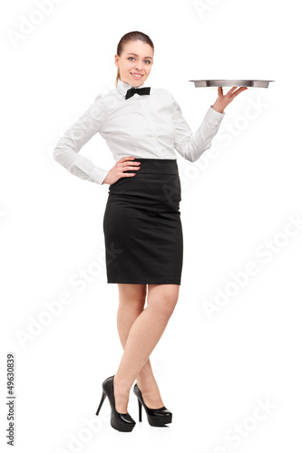 Photo: Full length portrait of a waitress with bow tie holding an empty Full length portrait of a waitress with bow tie holding an empty