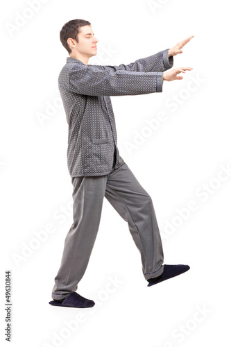 Photo: Full length portrait of a young man in pajamas sleepwalking Full length portrait of a young man in pajamas sleepwalking